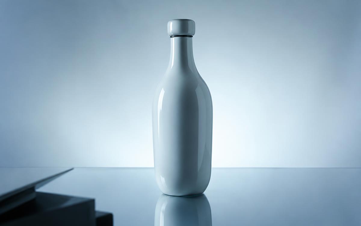 Glossy ceramic bottle on a reflective surface lit with cold light